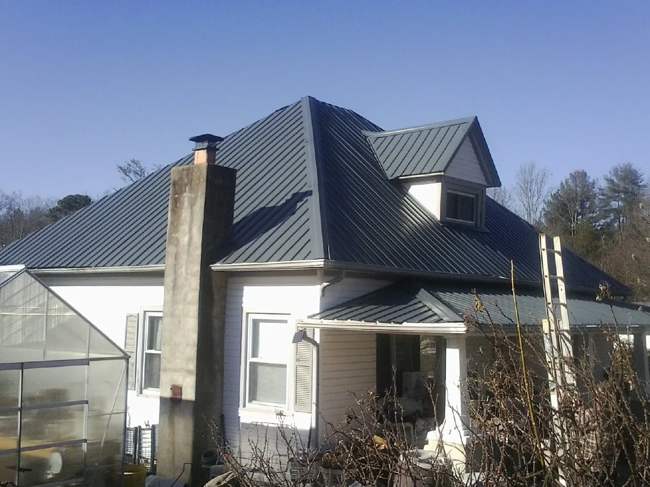 Dark blue standing seam metal roof on a white farmhouse with dormer — Slate & Tile Roof Repair by Roofing Brothers in Hickory Hills