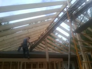 Rafters going up over a new addition with a worker on the wall in Hickory Hills