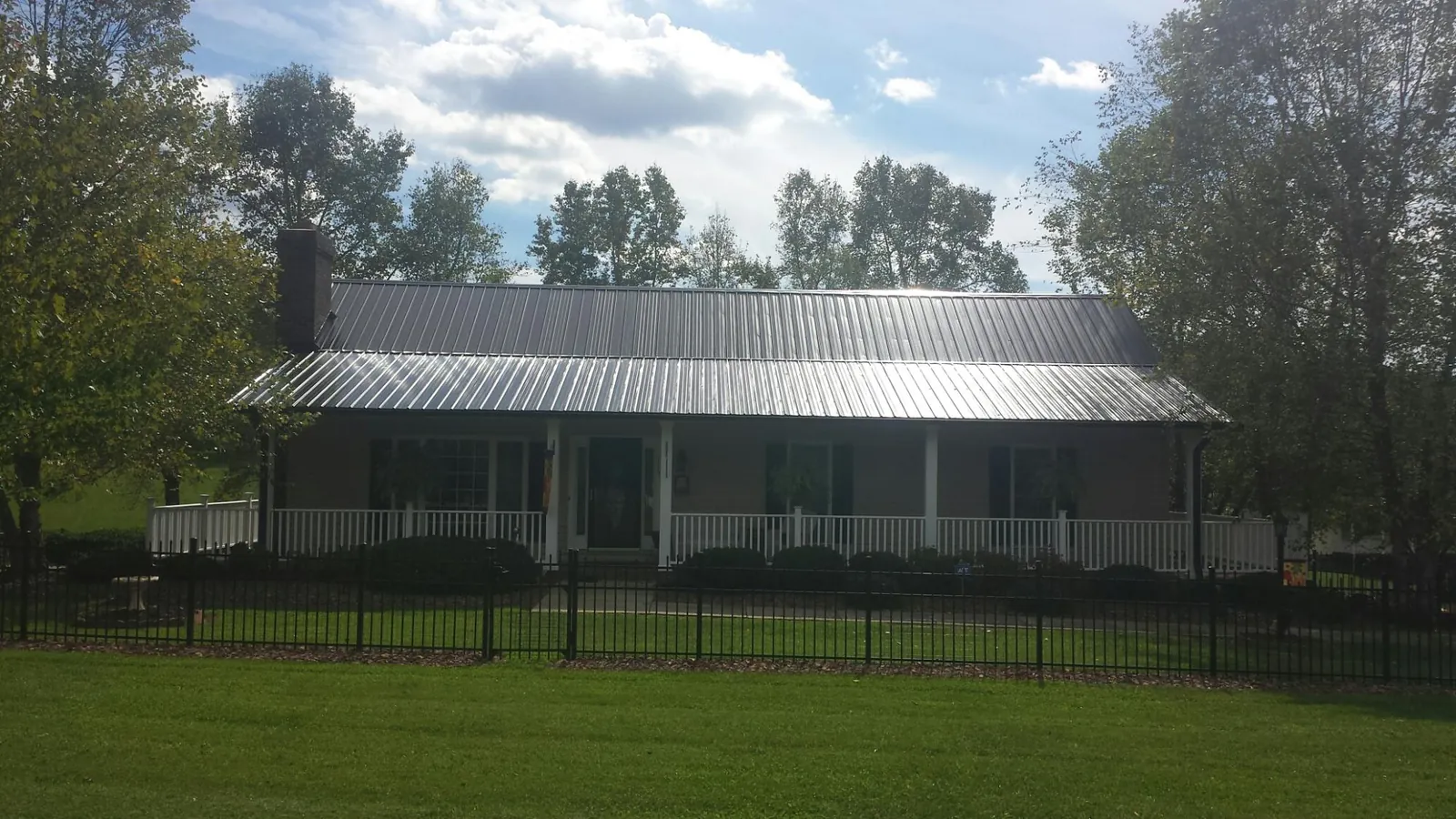 Gray metal roof on a brick ranch with a full width front porch — Gutter Guard Installation work by our crew in Hickory Hills