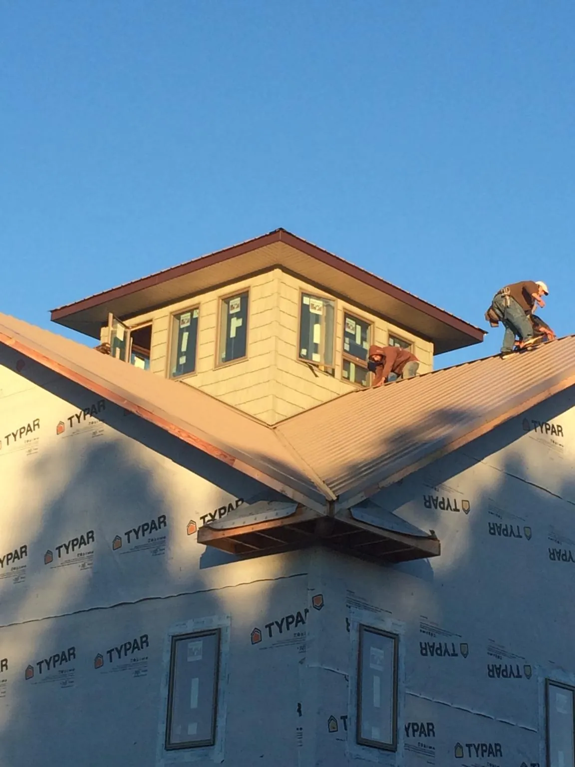 Roofers working around a rooftop cupola on a new metal roof at sunset — Roof Waterproofing in Hickory Hills by Roofing Brothers
